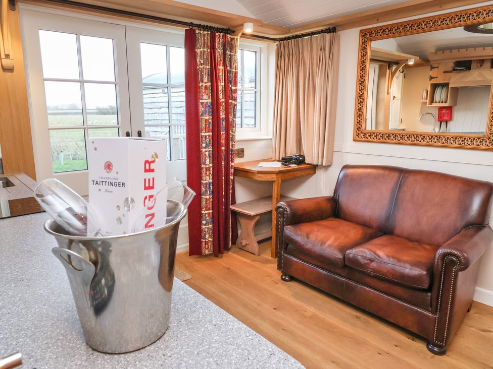 A living area with a brown leather sofa a small wooden table with a chair and a mirror on the wall at The White Princess in Bolton Percy near Tadcaster