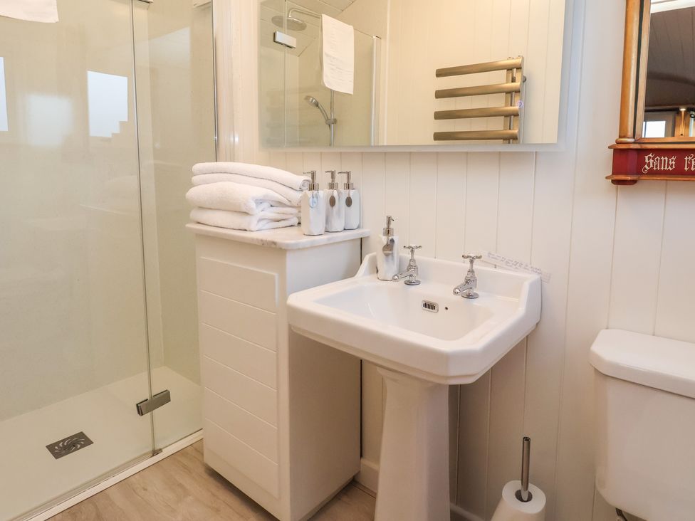 A bathroom with a shower, sink, toilet, towels, and soap dispensers at The White Princess in Bolton Percy near Tadcaster
