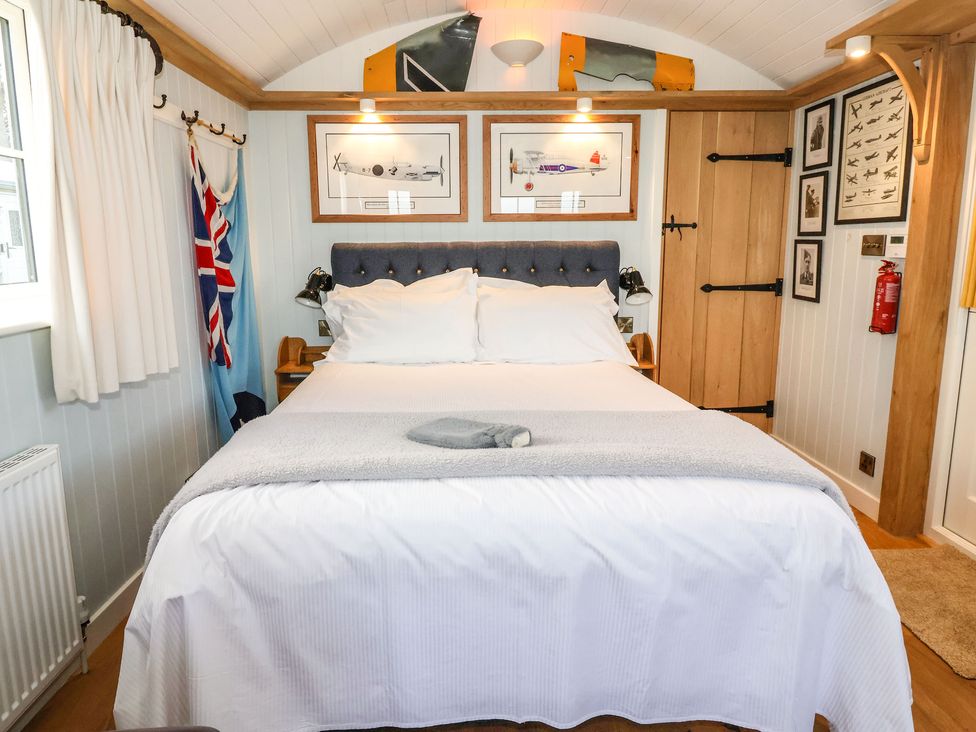 A bedroom with a double bed white bedding framed airplane drawings and wooden door at The Fenton in Bolton Percy near Tadcaster