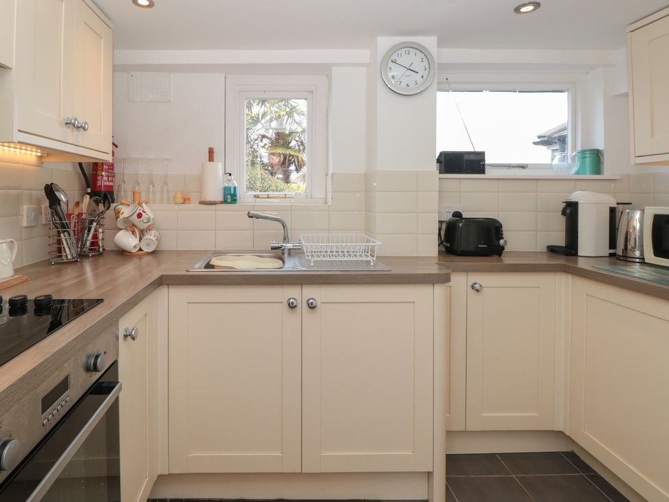 A kitchen with cream cabinets a sink cooking utensils and appliances at Dart Cottage in Dittisham