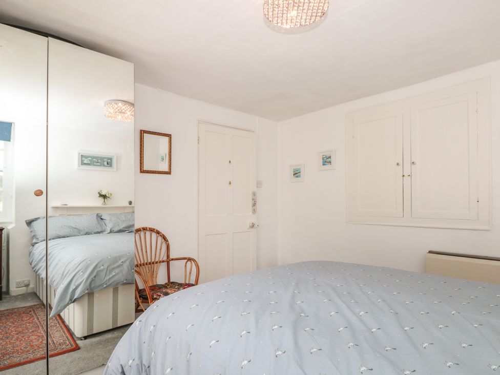 A bedroom with a bed covered with a blue duvet a mirrored wardrobe a wooden chair and framed pictures on the wall at Dart Cottage in Dittisham