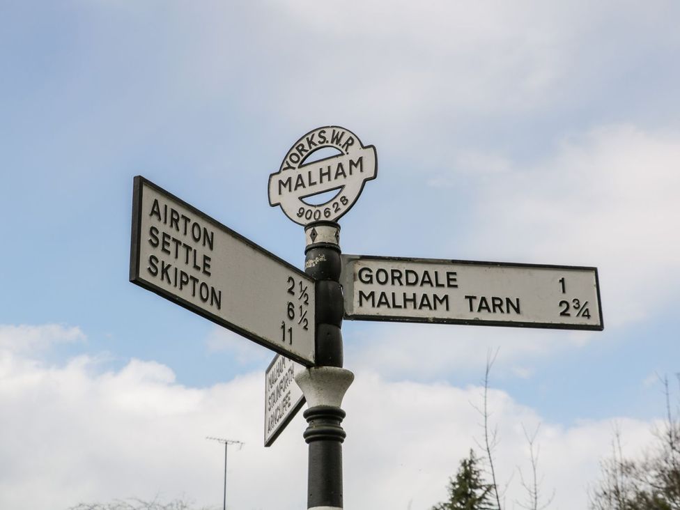 A directional signpost with distances to Airton Settle Skipton Gordale and Malham Tarn at The Hayloft at Tennant Barn in Malham