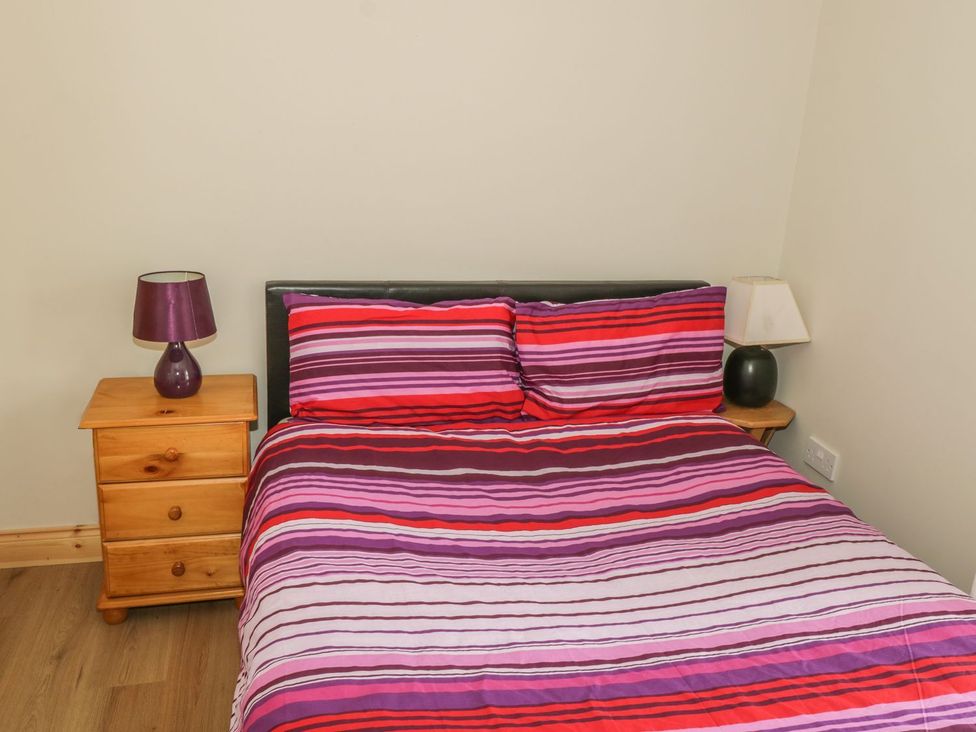 A bedroom with a double bed striped bedding and two wooden nightstands with lamps at Glebe House in Ballinrobe County Mayo