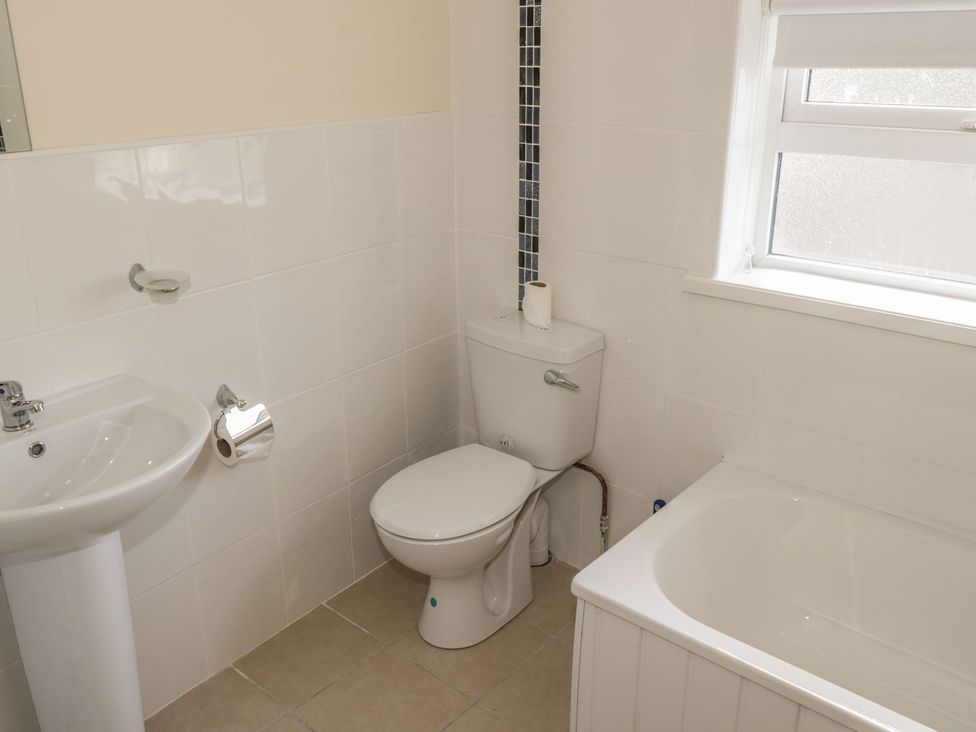 A bathroom with a white sink toilet and bathtub next to a window at Glebe House in Ballinrobe County Mayo