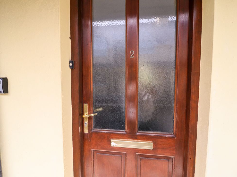 A wooden front door with frosted glass panels and a brass mail slot at 2 Garnish Court in Glengarriff County Cork