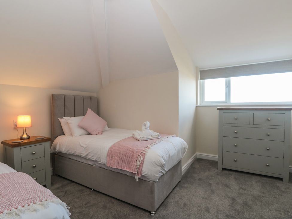 A bedroom with two single beds a bedside table with a lamp and a chest of drawers at Seapoint in Primrose Valley