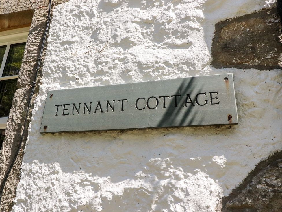 A sign with the text Tennant Cottage mounted on a white rough textured wall at Tennant Cottage in Malham