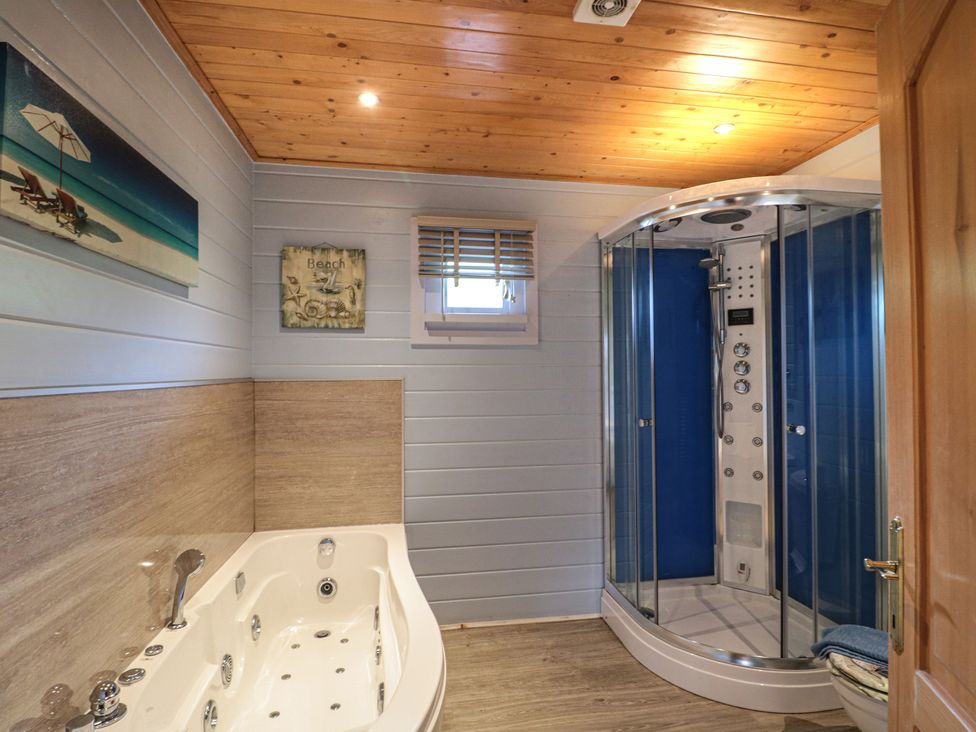 A bathroom with a bathtub shower cabin window and beach-themed wall art at Pine in Swanage