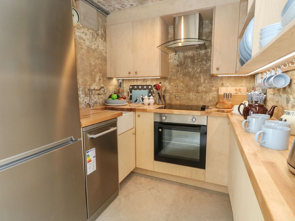 A small kitchen with wooden countertops and cabinets stainless steel appliances and assorted kitchenware at The Transmitter Bunker in Ringstead