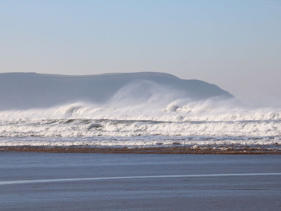 Waves crashing on a beach with hills in the background at Ocean Terrace 1 in Mullacott near Ilfracombe