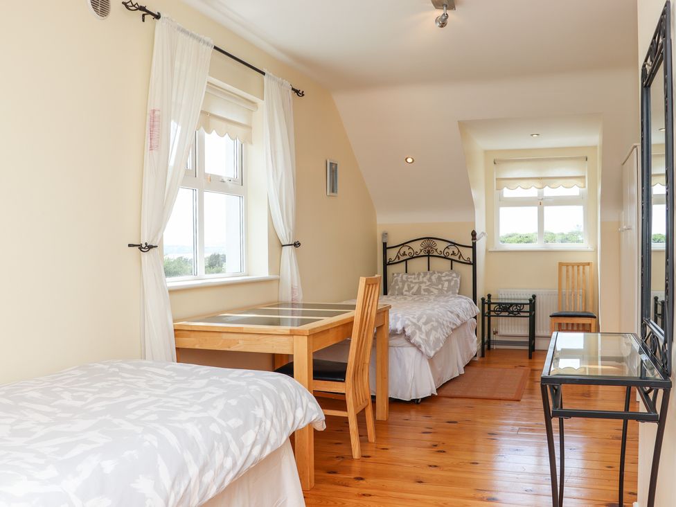 A bedroom with two single beds a wooden table and chairs and windows with white curtains at South Beach in Duncannon County Wexford