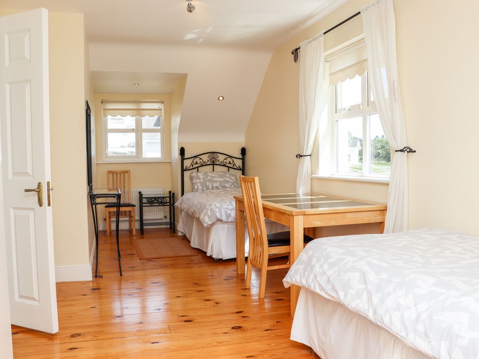 A bedroom with two single beds a wooden table with chairs and windows at South Beach in Duncannon County Wexford