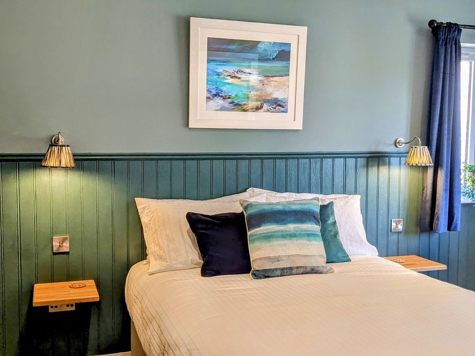 A bedroom with a bed with multiple cushions and a framed painting above at Taigh Moy in Gairlochy