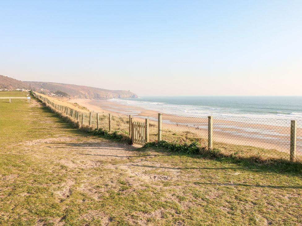 A coastal path with a wire fence and gate overlooking a sandy beach and ocean at Chi an Mor in Lower Kenneggy near Praa Sands