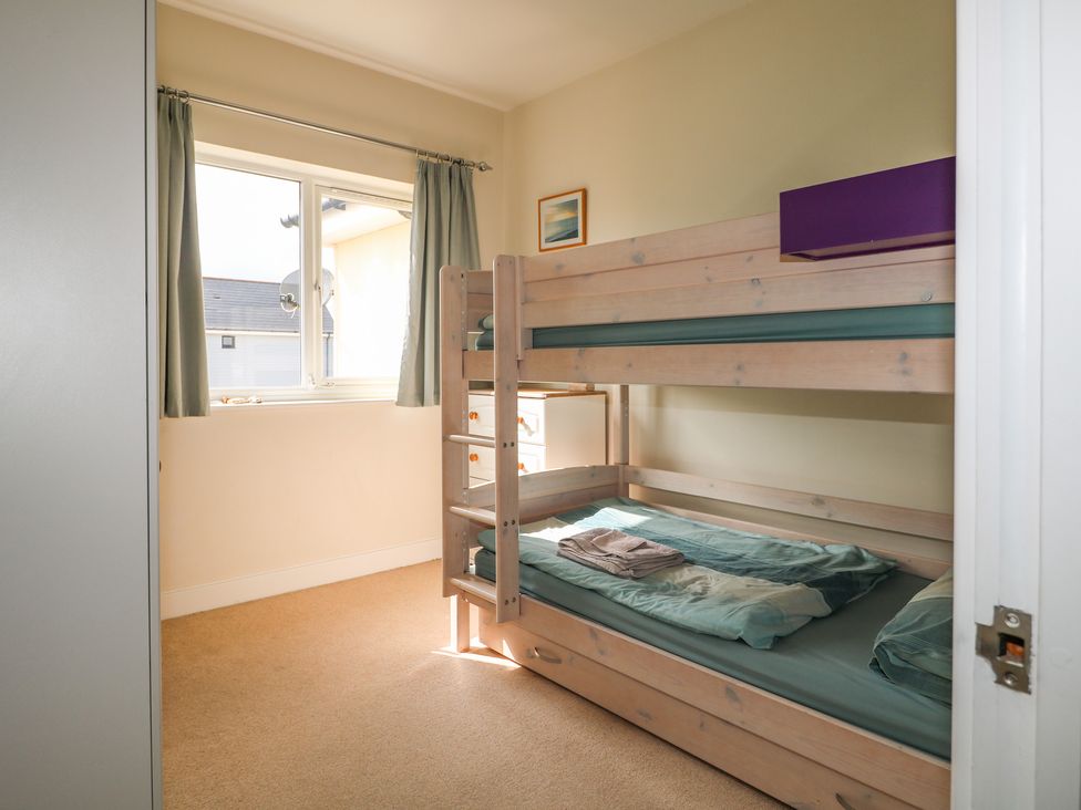 A bedroom with wooden bunk beds a window with curtains and a small chest of drawers at Pebble House in Worthing