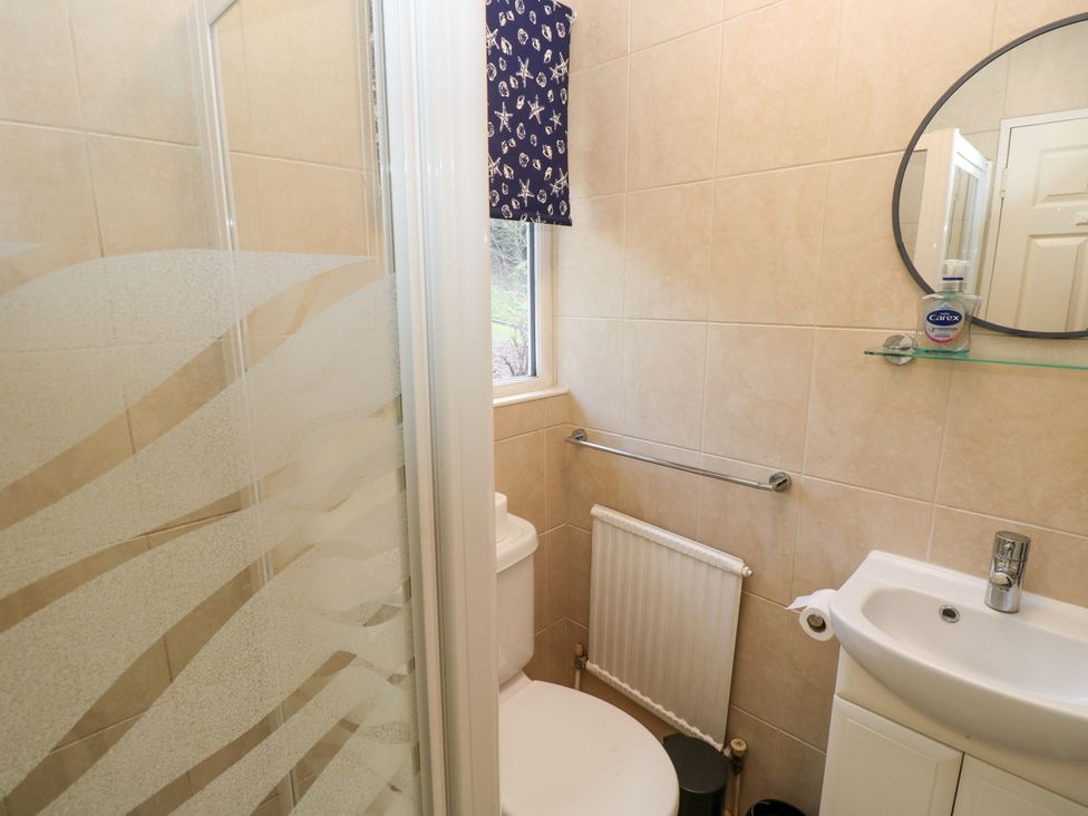 A small bathroom with a toilet shower sink mirror and window at Byewater in Ryde