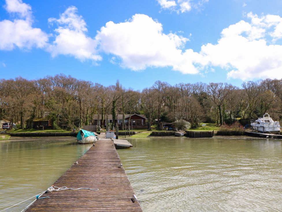 A wooden dock extending into a body of water with boats and trees in the background at Byewater in Ryde