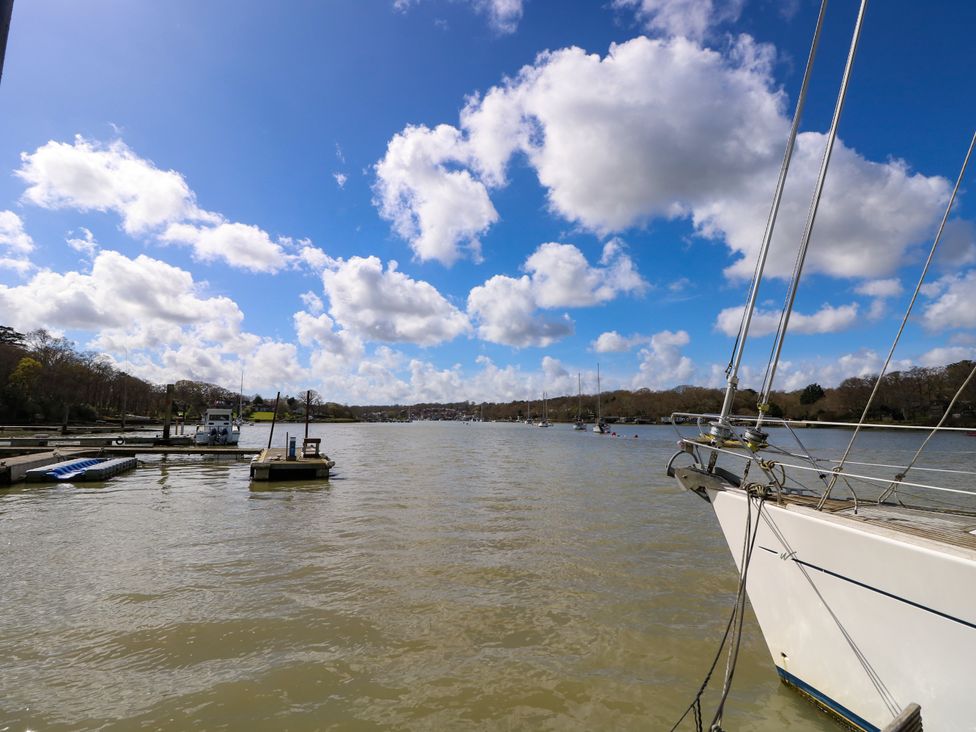 A river with boats docked and a boat bow in the foreground at Byewater in Ryde