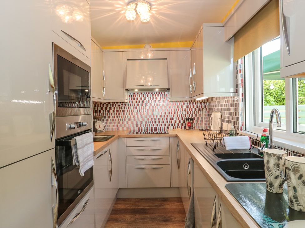 A kitchen with built-in oven microwave sink countertop cabinets and tiled backsplash at Foxes Den in Bournemouth