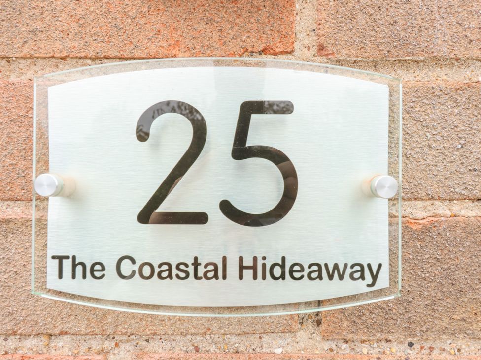 A house number sign with the number 25 and the text The Coastal Hideaway on a brick wall at The Coastal Hideaway in Hornsea
