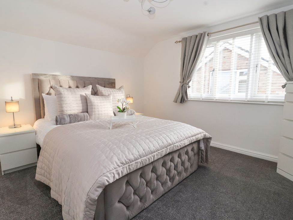 A bedroom with a bed pillows bedside tables lamps window with curtains at The Coastal Hideaway in Hornsea