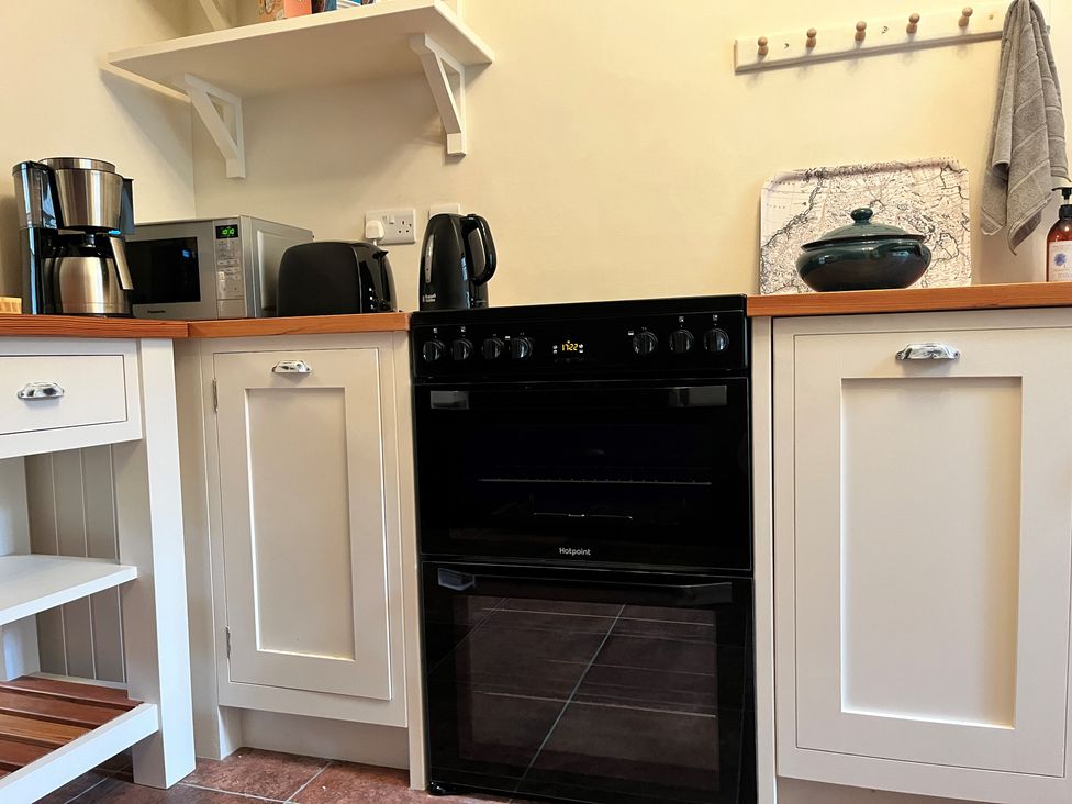 A kitchen with a black oven between white cabinets a microwave coffee maker toaster and kettle on the countertop at 5 Castle Hill in Lancaster