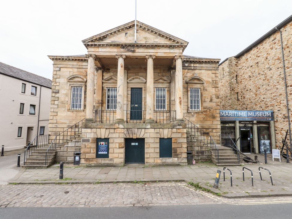 The front view of a stone building with pillars and stairs leading to a door showing a maritime museum sign in Lancaster