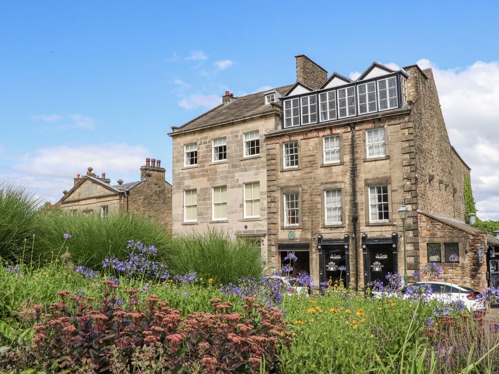 A historic stone building with multiple windows and flowering plants in front at 5 Castle Hill in Lancaster
