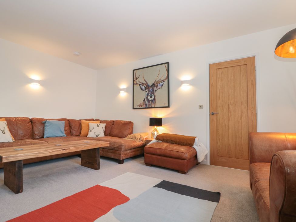 A living room with a brown leather sectional sofa wooden coffee table wall art of a deer and a wooden door at Bailey house in Pocklington