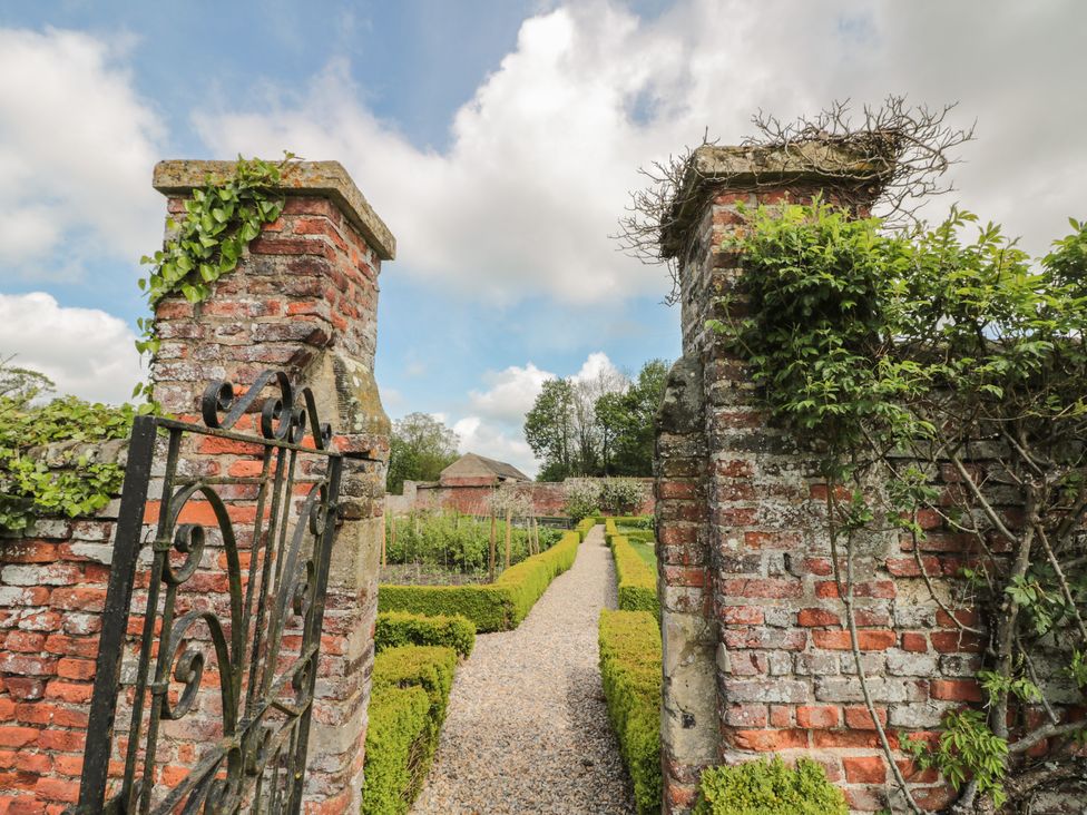 A pathway through a garden with trimmed hedges and brick gateposts at Bailey house in Pocklington
