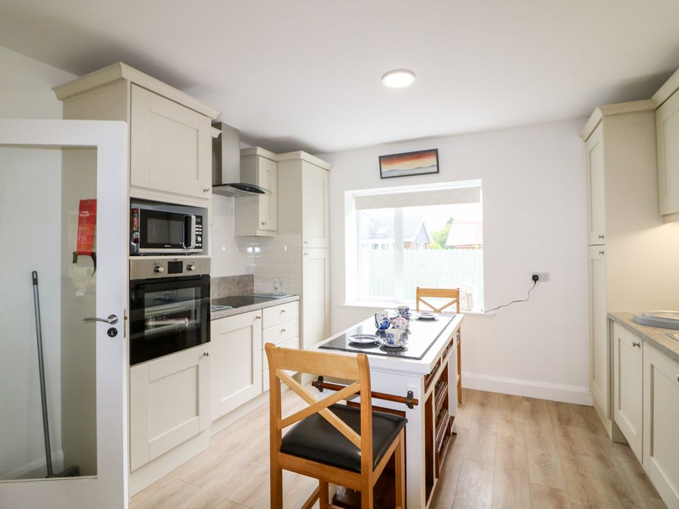 A kitchen with cabinets appliances a small island and two wooden chairs at Ahiohill Meadows Ahiohill near Ballinascarty County Cork