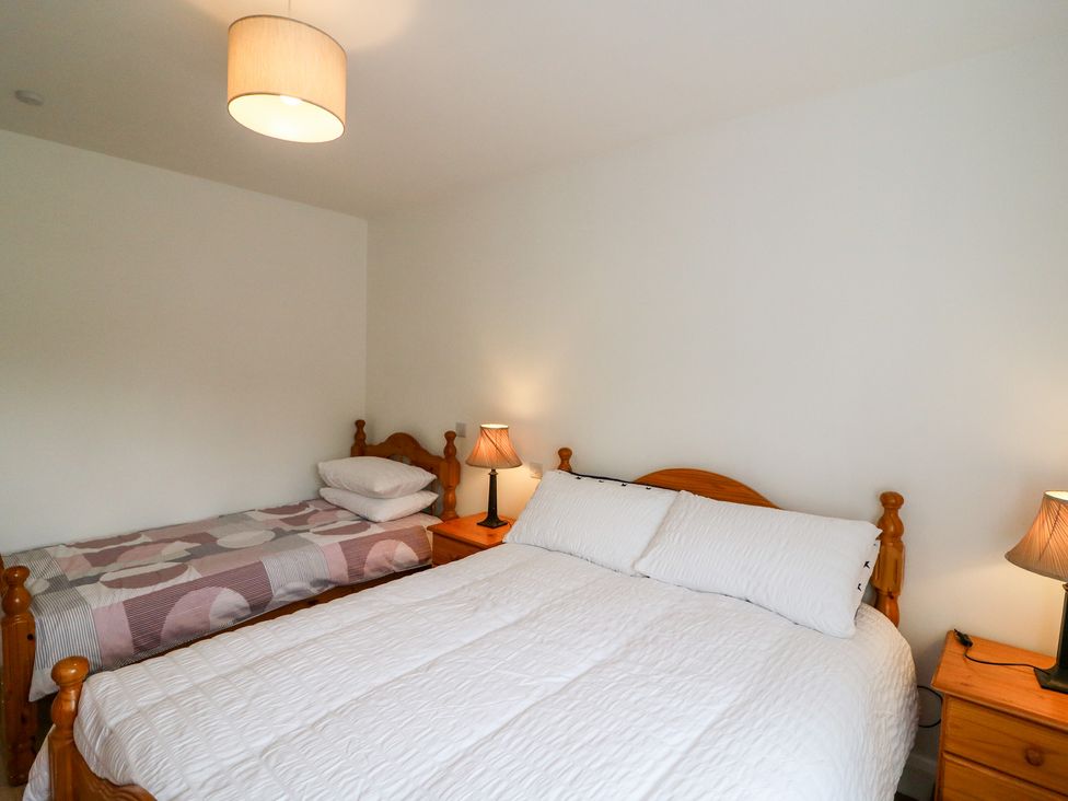 A bedroom with a double bed and a single bed with bedside tables and lamps at Ahiohill Meadows Ahiohill near Ballinascarty County Cork