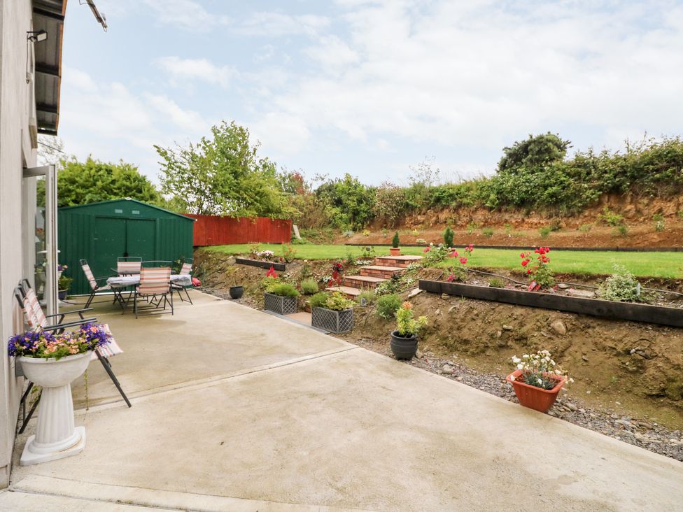 A garden patio with chairs tables flower pots and a green shed at Ahiohill Meadows Ahiohill near Ballinascarty County Cork