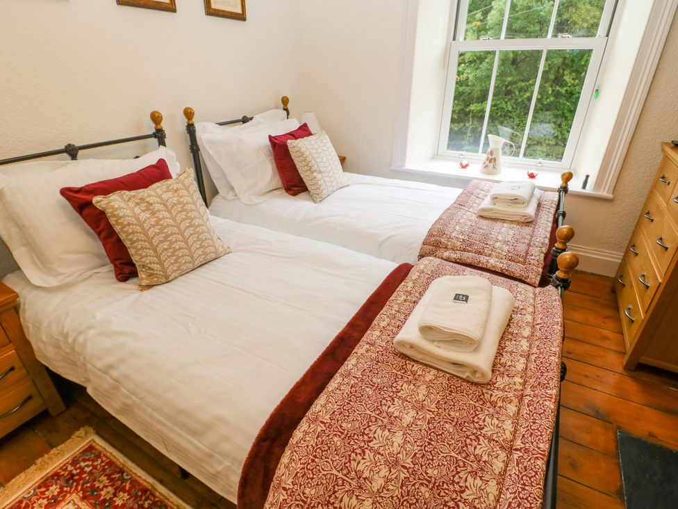 A bedroom with two single beds each with folded towels on top next to a window at Miss Burrow's House in Hawes