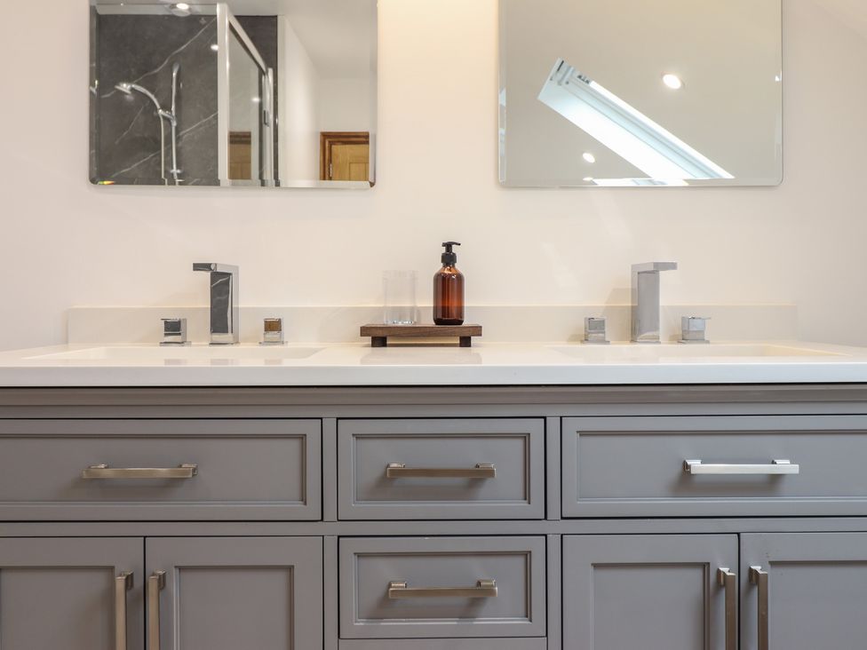 A bathroom vanity with two sinks two mirrors and a soap dispenser at Gaerau Bach in Llanaber