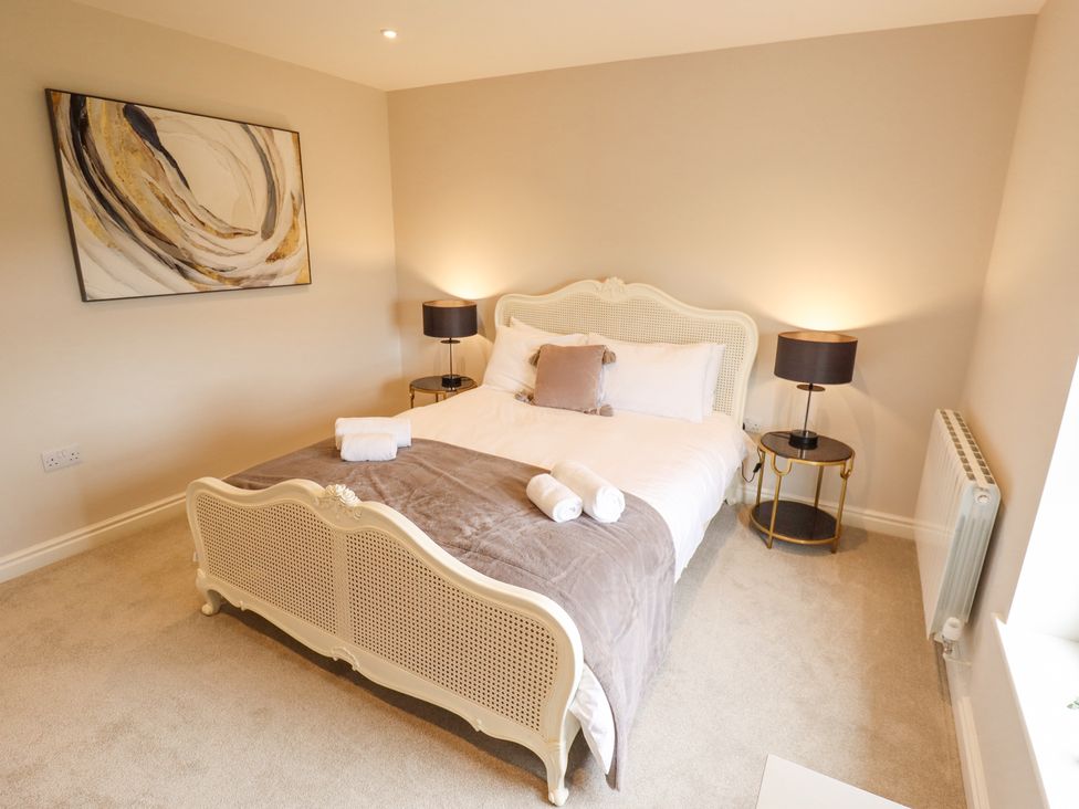 A bedroom with a double bed two bedside tables with lamps and a painting on the wall at Foremans Cottage in Withernsea