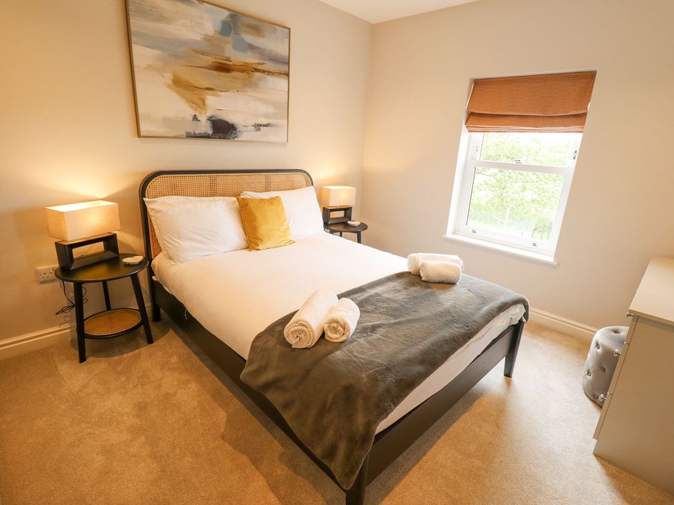 A bedroom with a double bed bedside tables lamps a window and a dresser at Foremans Cottage in Withernsea