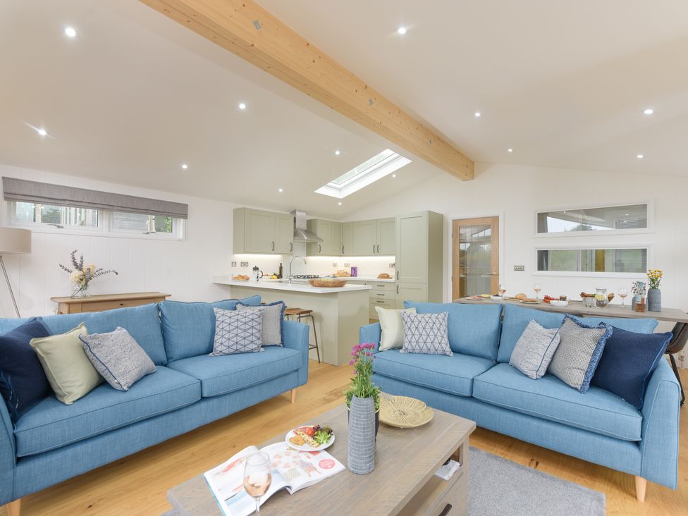 An open plan living room and kitchen with two blue sofas and a wooden coffee table at 4 Valley View in Lanreath