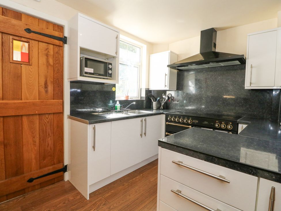 A kitchen with white cabinets black countertops a wooden door and a window above the sink at Callart View in Glencoe