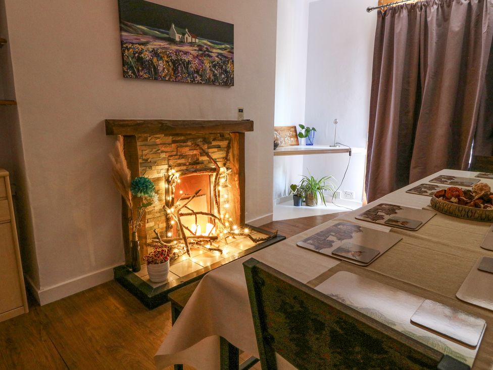 A dining room with a table set with placemats next to a fireplace with decorative lights and plants at Callart View in Glencoe