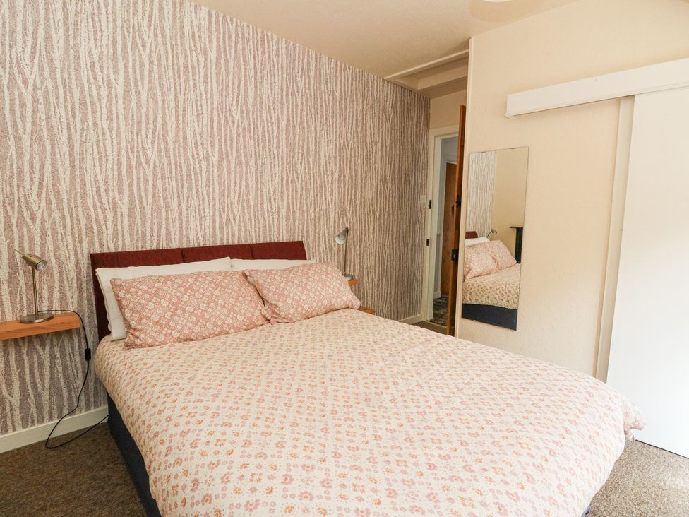 A bedroom with a double bed patterned wallpaper and a mirror on the wall at Callart View in Glencoe
