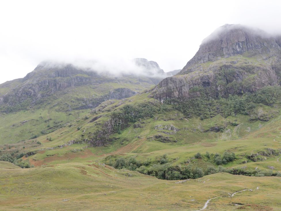 A view of mountains with grassy slopes and patches of trees at Callart View in Glencoe