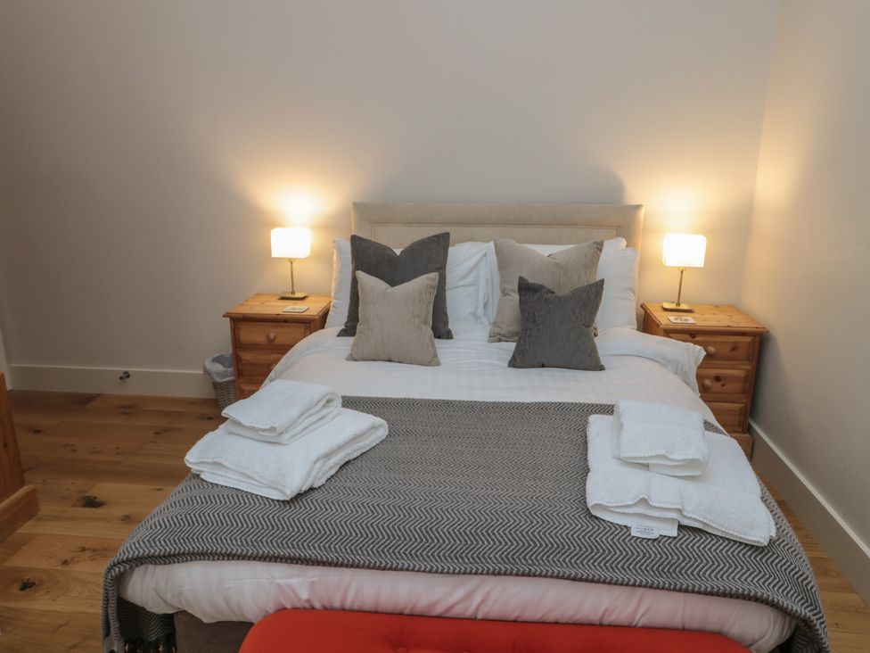 A bedroom with a bed with pillows and towels bedside tables with lamps on each side at The Coach House in Bamburgh