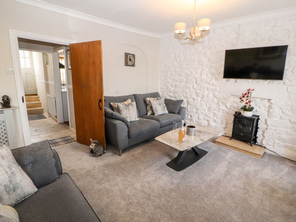 A living room with gray sofas a wall-mounted TV and a coffee table at Market Square Maisonette in Kirkby Lonsdale