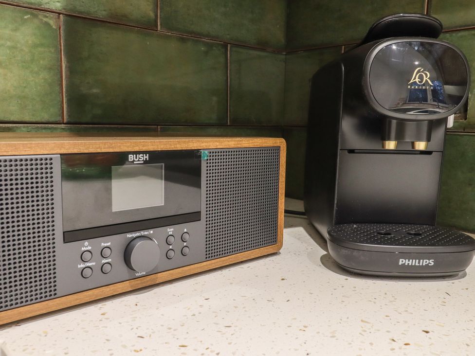 A kitchen countertop with a Bush radio and a Philips coffee machine with green tiled wall at Mabel in Whitstable
