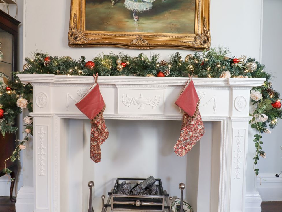 A white fireplace decorated with green garlands and Christmas stockings at 3 Old Market Place in Harleston