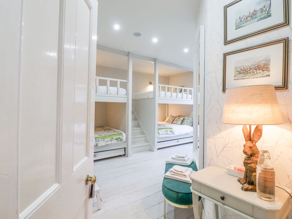 A bedroom with bunk beds towels on a bench lamp on a table and framed pictures on the wall at 3 Old Market Place in Harleston