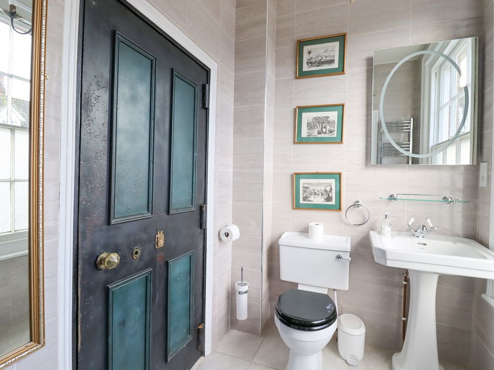 A bathroom with a white toilet and sink a black door and framed pictures on the wall at 3 Old Market Place in Harleston