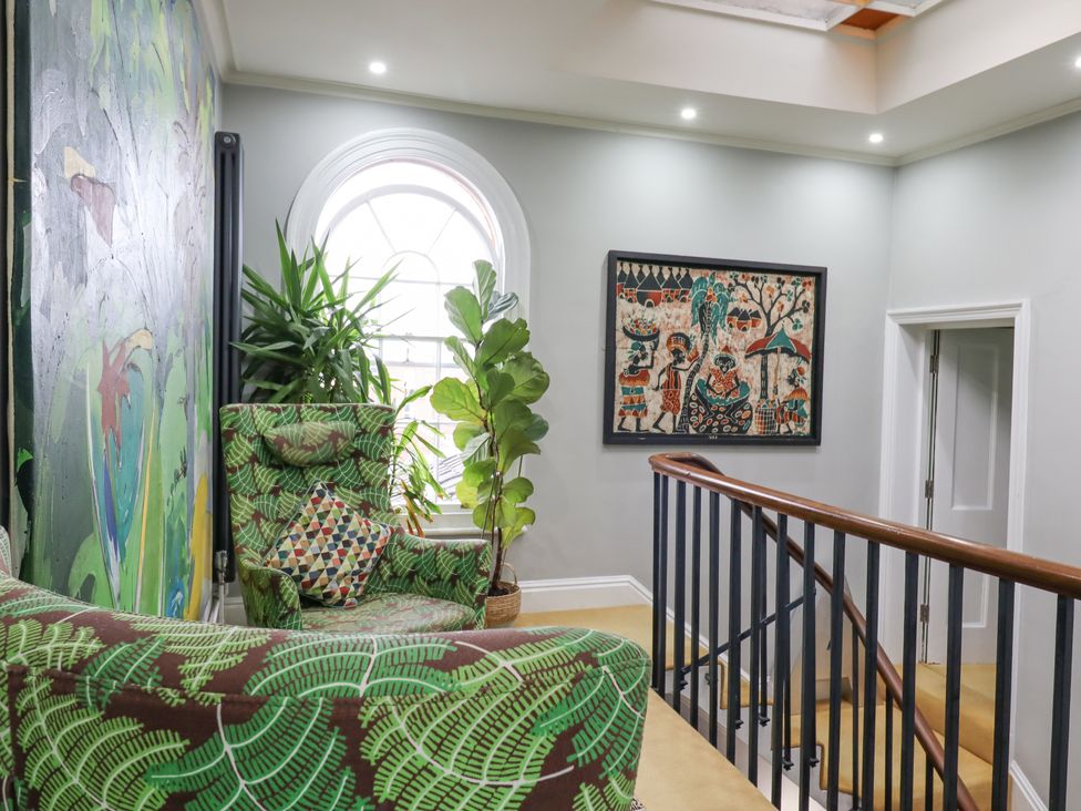 An upstairs sitting area with patterned armchairs plants and framed artwork on walls at 3 Old Market Place in Harleston