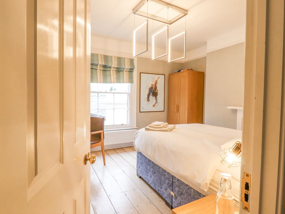 A bedroom with a bed, wooden wardrobe, chair, window with striped blinds and modern ceiling lights at 3 Old Market Place in Harleston